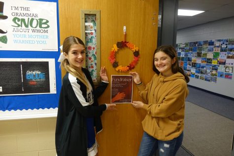 8th graders Jadyn Barnett & Lucy Hundley hang up posters for the WRMS WERC Program’s Fundraiser. They are raising money to help build a new school in Rwanda. 20% of the funds will go to help  Imana Kids, a program that helps street kids and orphans. The owners, Kira and Ryan Higgins, have the plans to open a trauma informed school, foster care homes, community center and health clinic. Caption by MyLee Mullins.