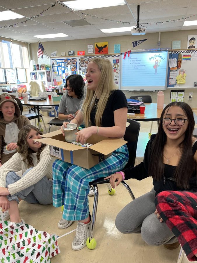 8th grade newspaper student Jolie Workman laughs with classmates Jayla Cruz, Sarah Whitaker, and MyLee Mullins as they participate in a White Elephant gift exchange on Friday, December 16th. The most popular gifts were a lava lamp/Skittles combo and blow-up boxing gloves.