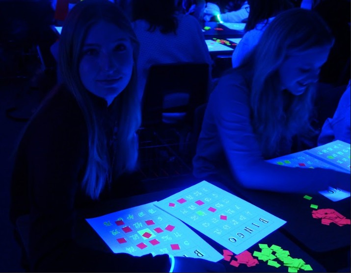 On Thursday, March 9th, 8th graders Jarah Dodder & Jolie Workman from the Wave team play Black-light Bingo in Mrs. Rainey’s room during the rotations to celebrate the end of 3rd quarter. Caption by Shiah Simpson.