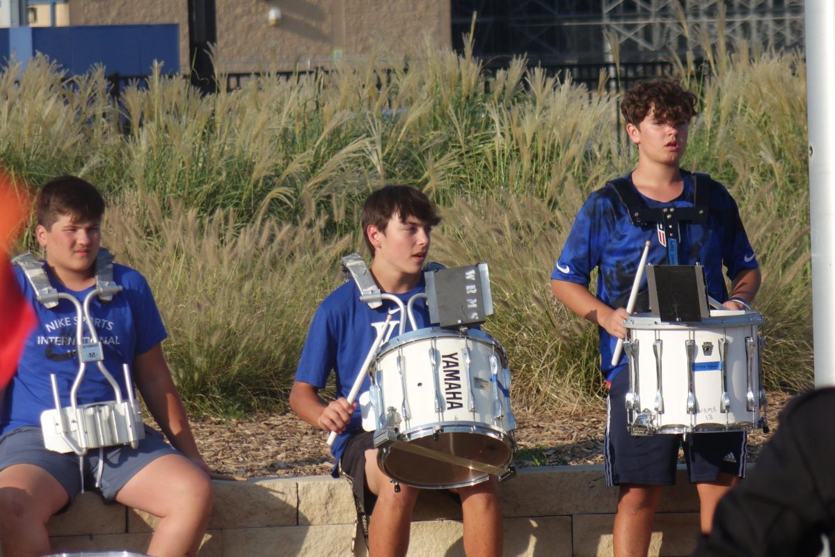 On Friday, September 8th, Elijah Ekis, Aiden Yocum, and Jaxson Adams attentively watch the band teacher for instruction on the pregame band performance at Washburn Rural High School.