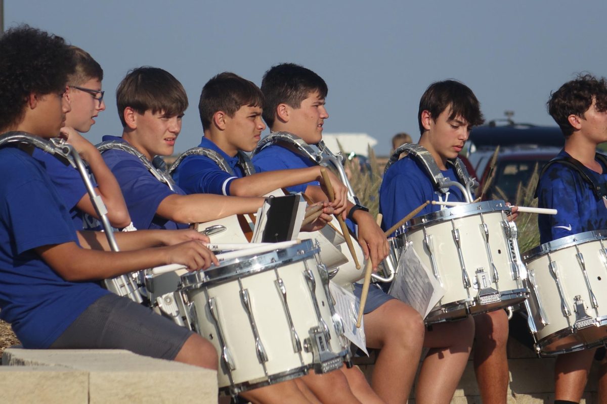 On September 8th, the WRMS drum line watches a high school band teacher intently, while waiting to get into formation at a pregame band performance, at Washburn Rural High school.