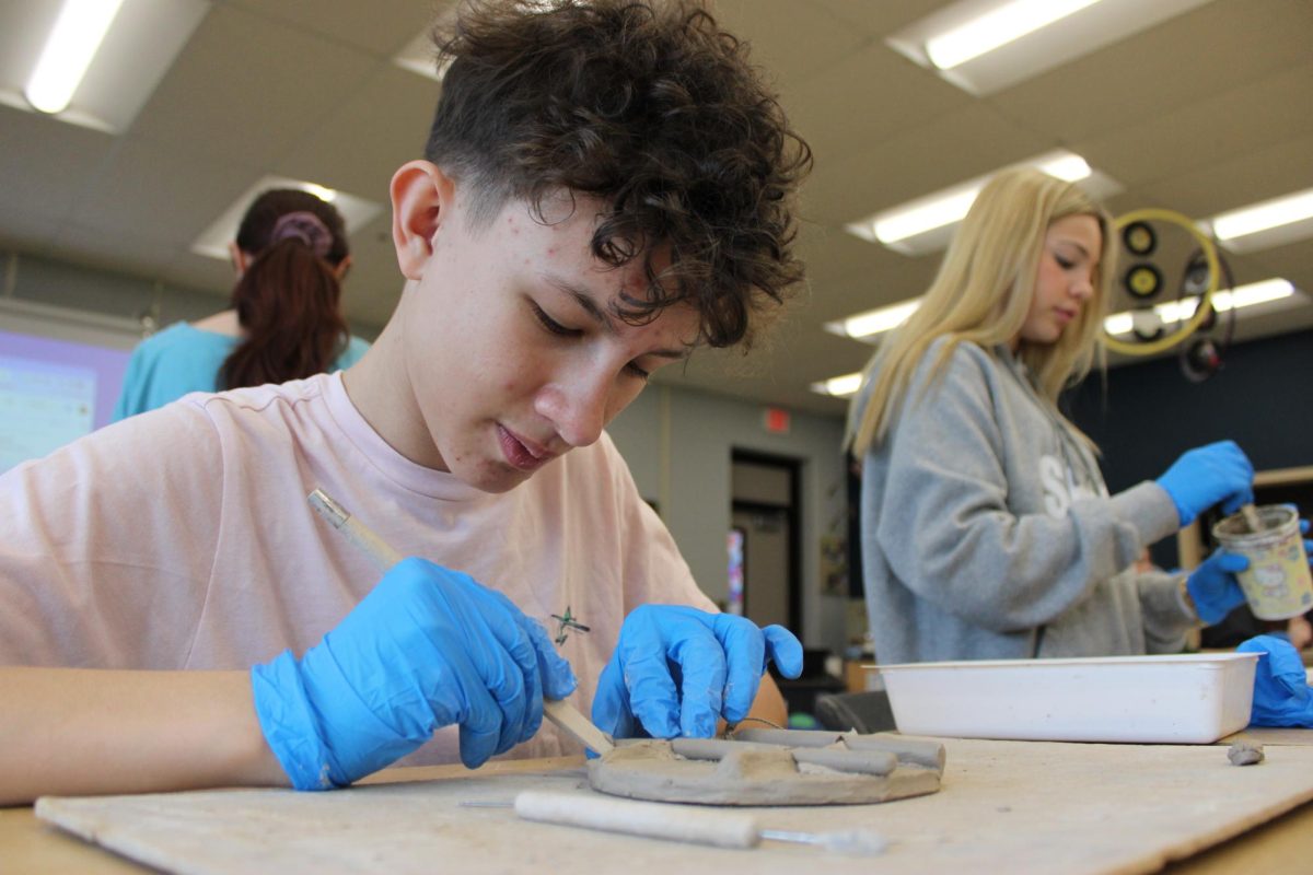 On February 6th, 8th grader Patrick Buster was in the WRMS art class, molding clay with a scraper, to smooth out the clay, for a Tic-Tac-Toe board assignment.