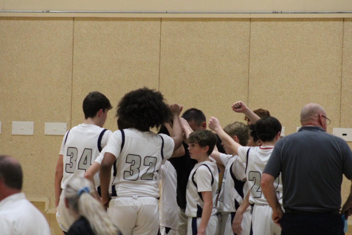 The 7th grade basketball team huddle up during a time-out around the end of the game. This game was a close call, but ended up winning. 
