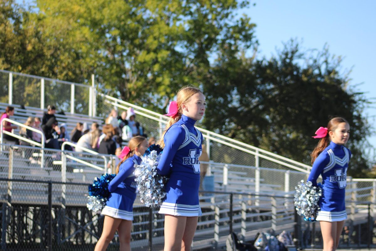 On Oct. 15, seventh grade cheerleaders, Olivia Guccione, Blake Classi, and Sophia Heble watch the intense game of WRMS vs. Shawnee Heights. Guccione said that she would want more football games if they could have them. “I would add more football games because we only got to do three.” 