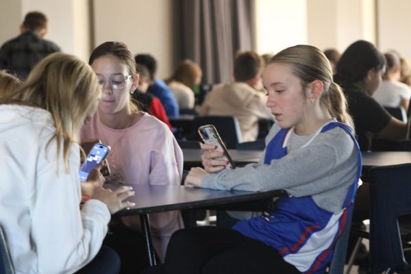 In the cafeteria, Lexi Walker, Aivha Knight, and Preslee Kirkwood play on their phones during 7th grade fast time on Nov. 12. 
