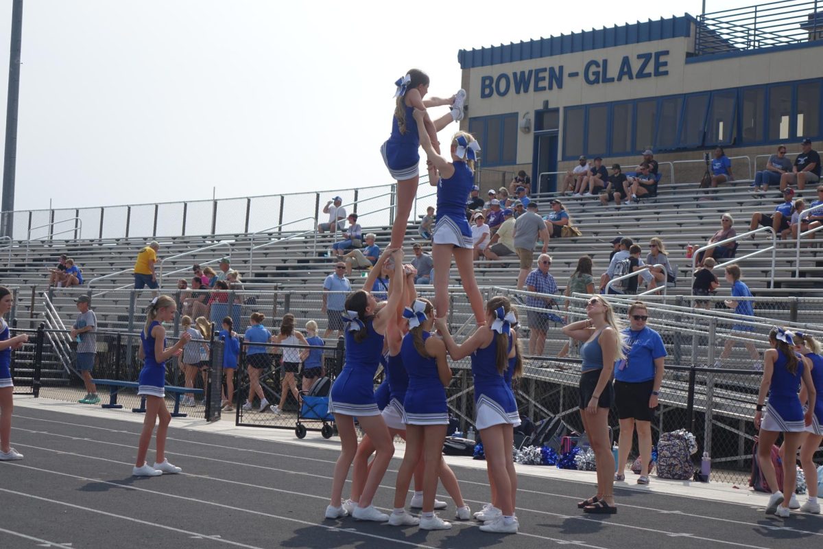 On Sept. 12, Hadley Rosenbaum, Kate Carter and the eighth grade cheer team perform a heel stretch at the WRMS football game. 