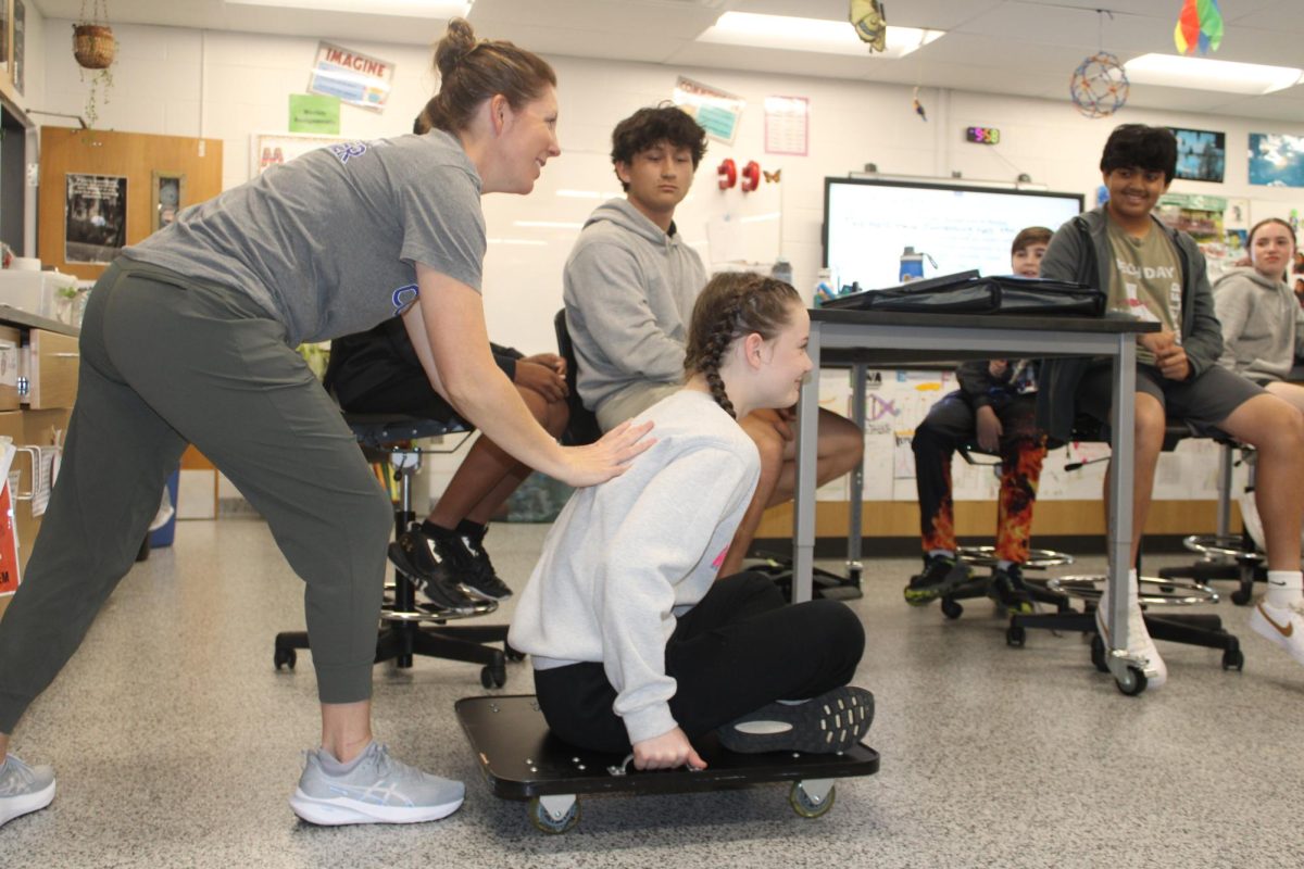 All Stars Science teacher Mrs. Campbell pushes seventh grader Corinne Parker in 3rd hour on a scooter to demonstrate Newton's second law. Parker says “I like learning about newton's laws because we get to use real life examples.”
