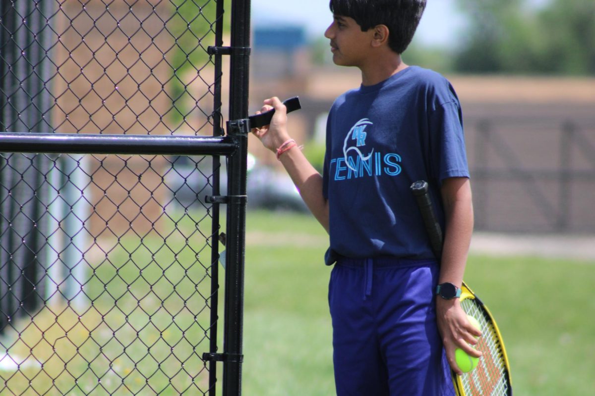 Seventh grader Parv Patel opens the gate to enter the court before a game on April 28 at the Washburn Rural High School tennis courts.